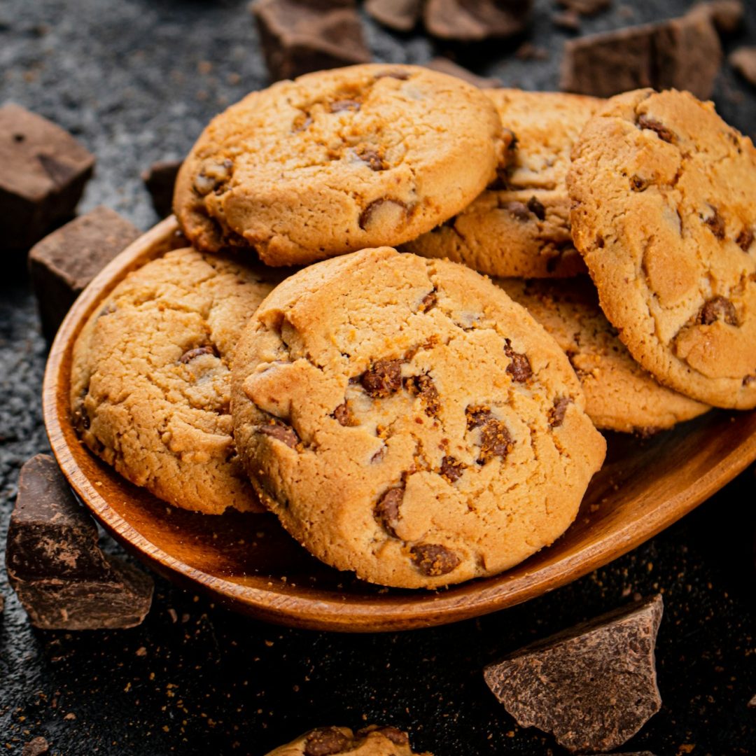 Wooden plate with cookies and pieces of milk chocolate.